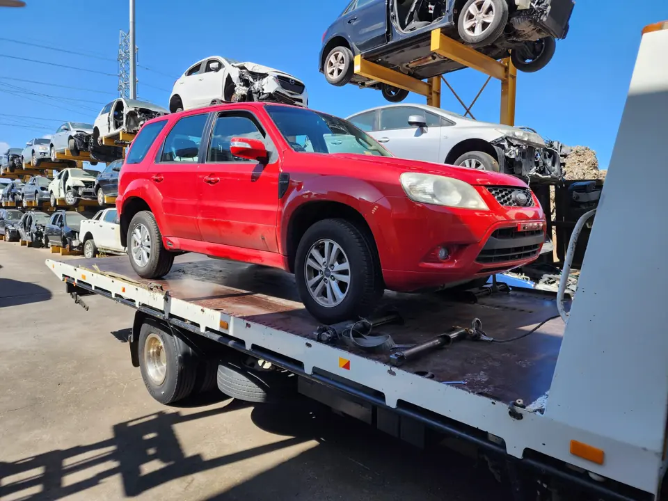 Red SUV loaded for transport in a vehicle yard