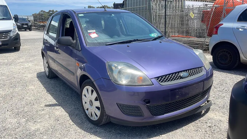 Blue compact hatchback in a vehicle yard