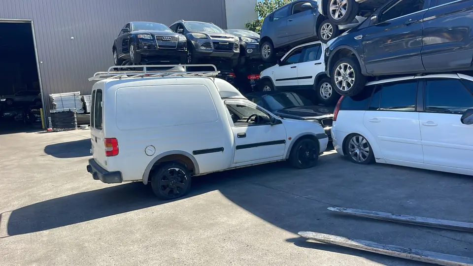 White work vehicle beside parked cars