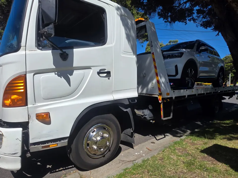 White recovery truck carrying a car