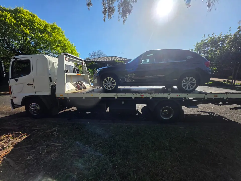 Dark car on a flatbed in sunlight