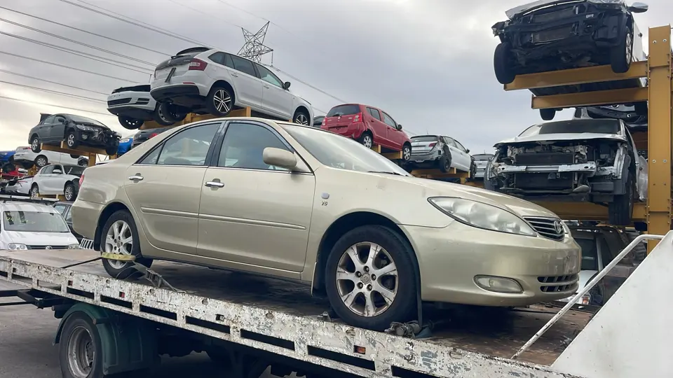 Light coloured sedan among vehicles
